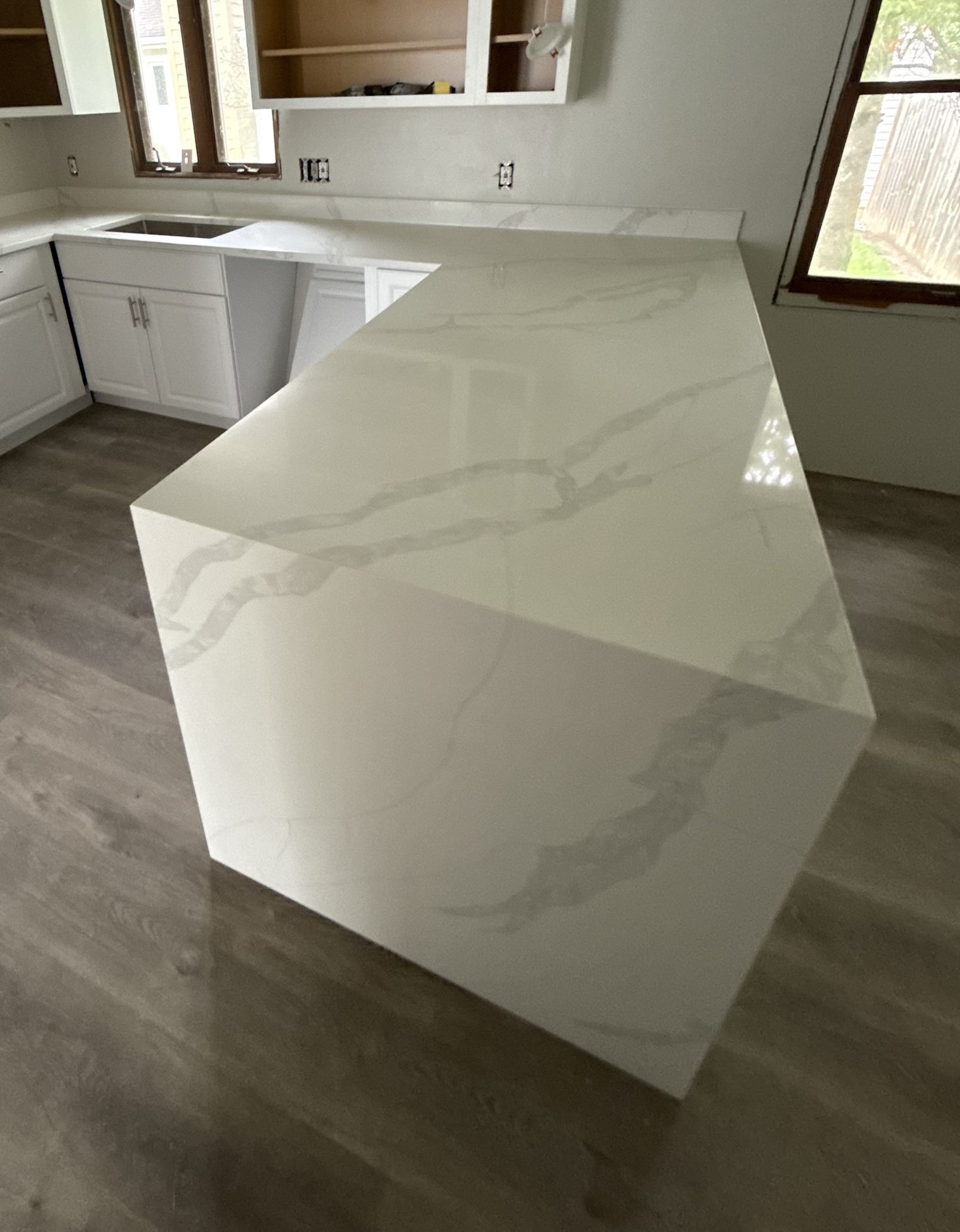 L-shaped Calacatta quartz peninsula with a mitered waterfall end, bold grey veins running across the top and down the side panel
